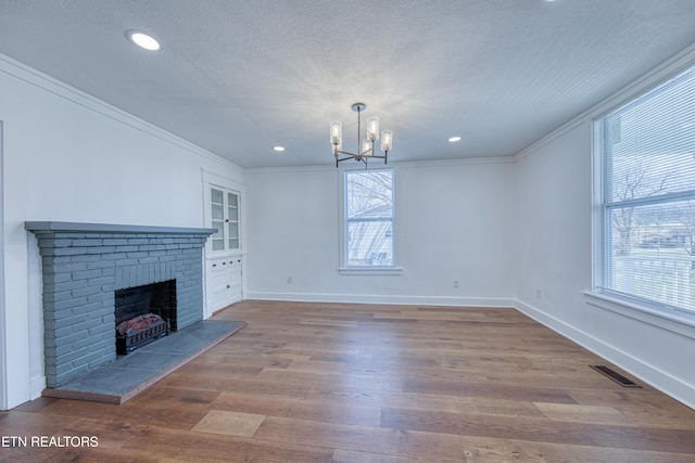 unfurnished living room featuring a textured ceiling, wood finished floors, visible vents, and ornamental molding