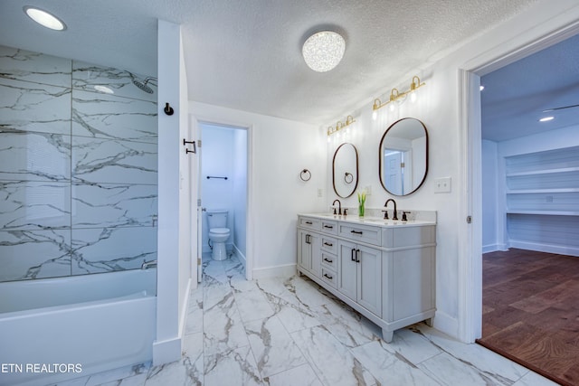 bathroom featuring a sink, a textured ceiling, marble finish floor, and double vanity