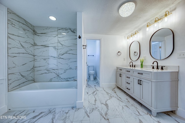 full bathroom with toilet, double vanity, marble finish floor, a textured ceiling, and a sink