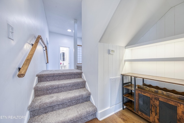 staircase featuring baseboards, wood finished floors, and vaulted ceiling