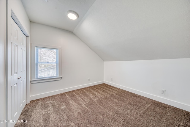 bonus room with a textured ceiling, lofted ceiling, baseboards, and carpet floors