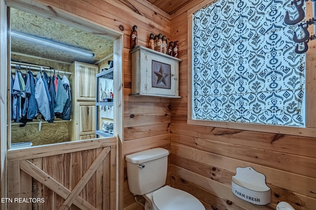 bathroom with toilet and wood walls