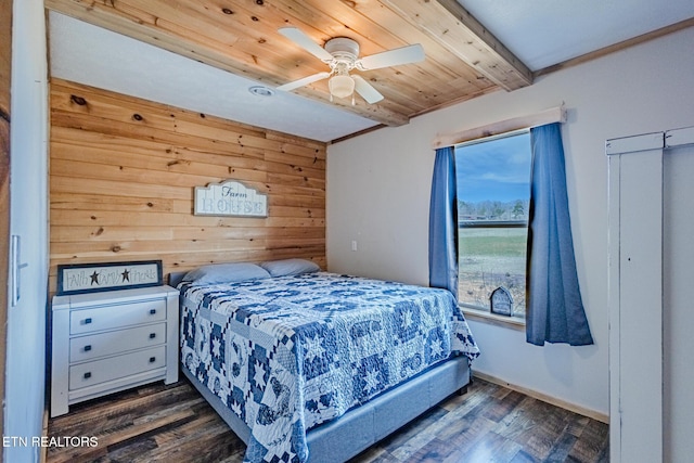 bedroom featuring dark wood finished floors, wooden walls, a ceiling fan, and beamed ceiling