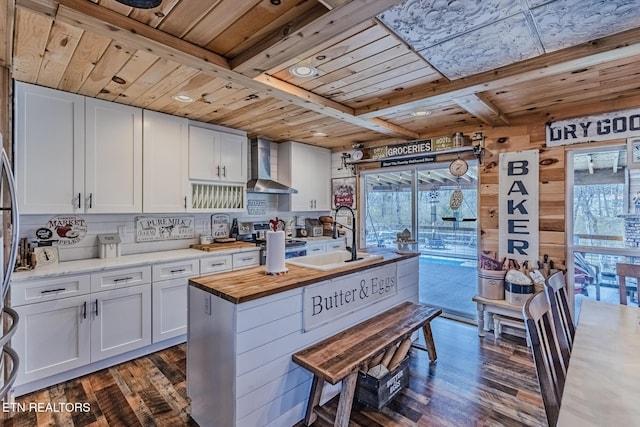 kitchen with a sink, wood ceiling, wood counters, gas range, and wall chimney exhaust hood