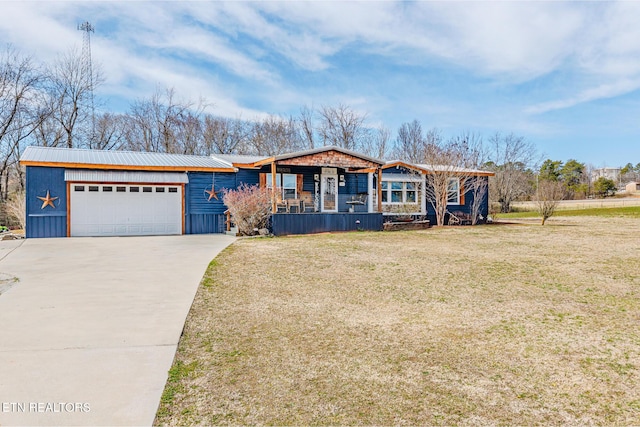 view of front of home featuring a garage, concrete driveway, a front yard, and metal roof