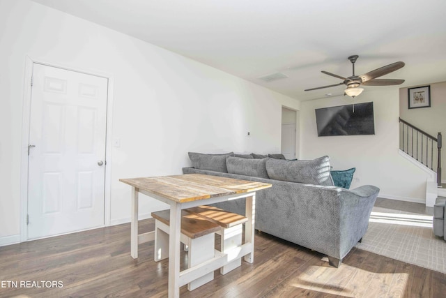 living area with baseboards, a ceiling fan, wood finished floors, and stairs