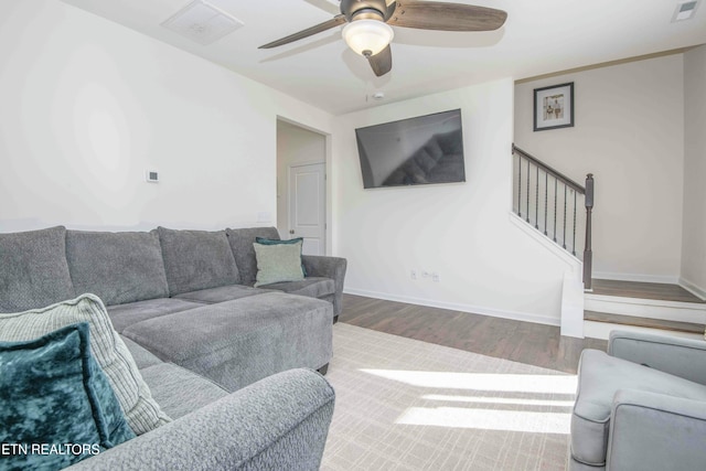 living room featuring stairway, a ceiling fan, wood finished floors, visible vents, and baseboards