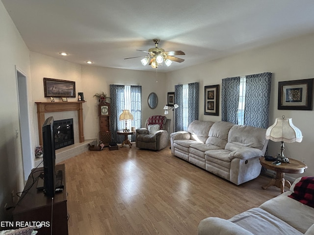 living area with ceiling fan, wood finished floors, a glass covered fireplace, and recessed lighting