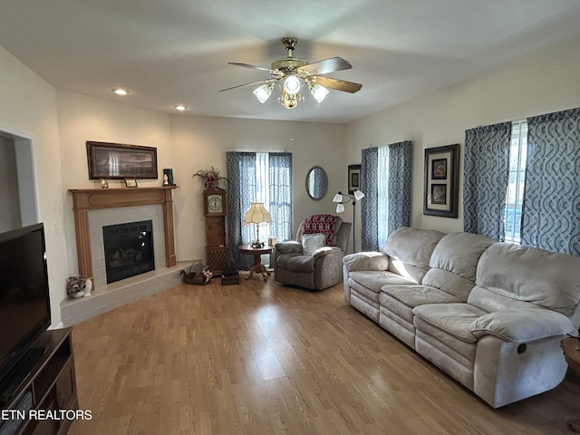 living room featuring a ceiling fan, recessed lighting, wood finished floors, and a tile fireplace