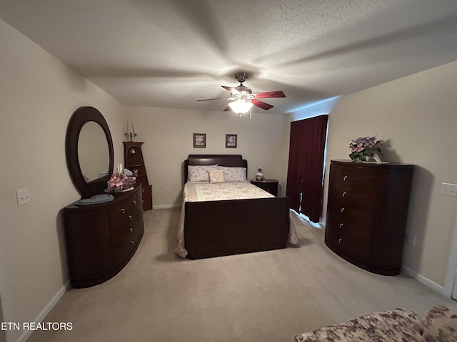 bedroom with light colored carpet, baseboards, a textured ceiling, and a ceiling fan