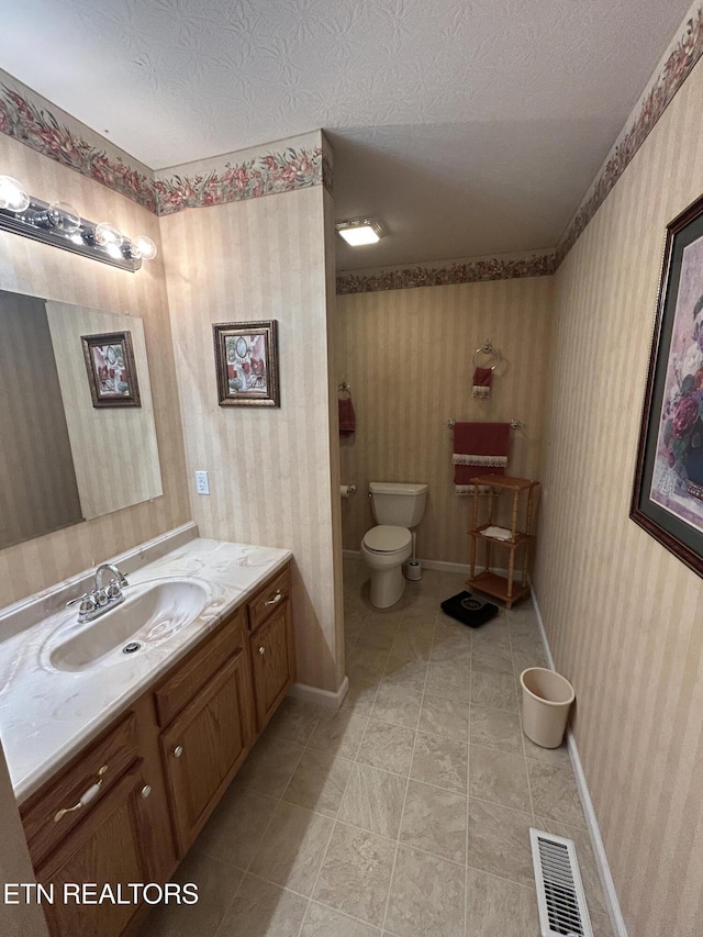 bathroom featuring visible vents, toilet, a textured ceiling, and wallpapered walls