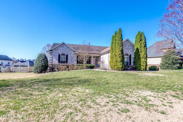 view of front of home featuring a front lawn, fence, and brick siding