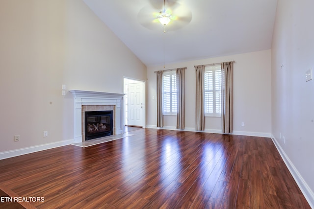 unfurnished living room featuring a ceiling fan, dark wood-style floors, baseboards, high vaulted ceiling, and a tiled fireplace