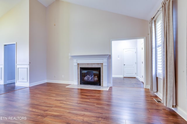 unfurnished living room featuring a fireplace, wood finished floors, visible vents, and high vaulted ceiling