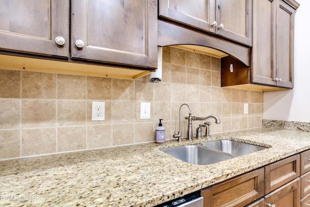 kitchen featuring light stone counters, backsplash, and a sink