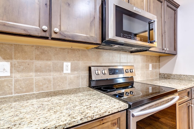 kitchen with light stone counters, tasteful backsplash, and appliances with stainless steel finishes