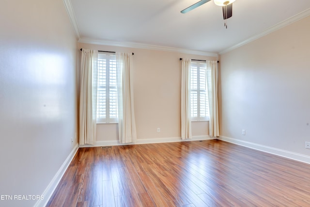 spare room with a wealth of natural light, wood finished floors, and crown molding