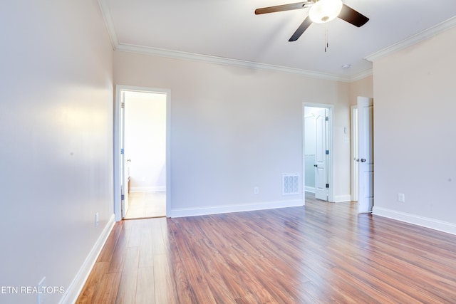 unfurnished room with visible vents, baseboards, wood finished floors, and ornamental molding