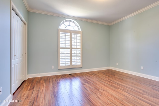 interior space with visible vents, crown molding, baseboards, wood finished floors, and a closet