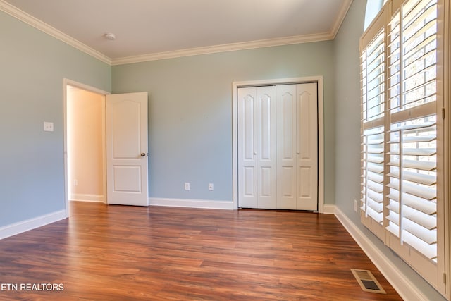 unfurnished bedroom featuring visible vents, baseboards, dark wood-style floors, and crown molding