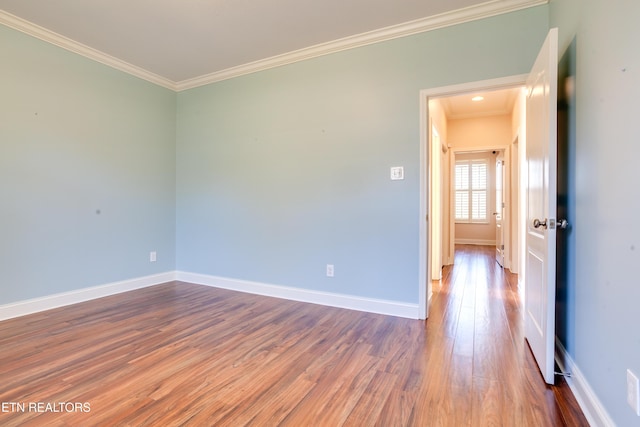 spare room featuring baseboards, wood finished floors, and ornamental molding