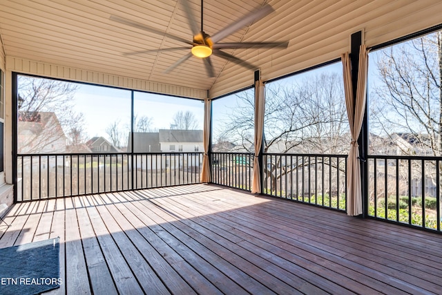 unfurnished sunroom with plenty of natural light, a ceiling fan, and vaulted ceiling