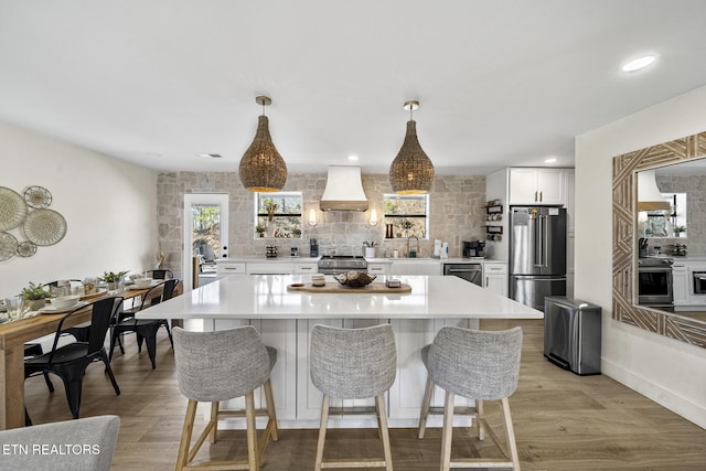 kitchen with custom exhaust hood, light countertops, tasteful backsplash, and stainless steel appliances