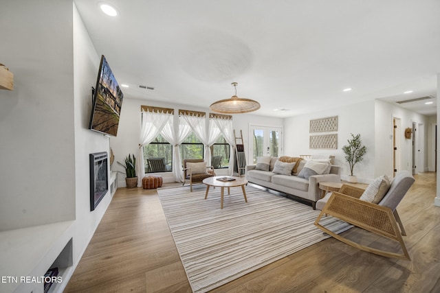 living room featuring visible vents, recessed lighting, light wood-type flooring, and a glass covered fireplace