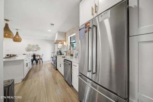 kitchen with light wood finished floors, visible vents, stainless steel appliances, custom exhaust hood, and white cabinetry