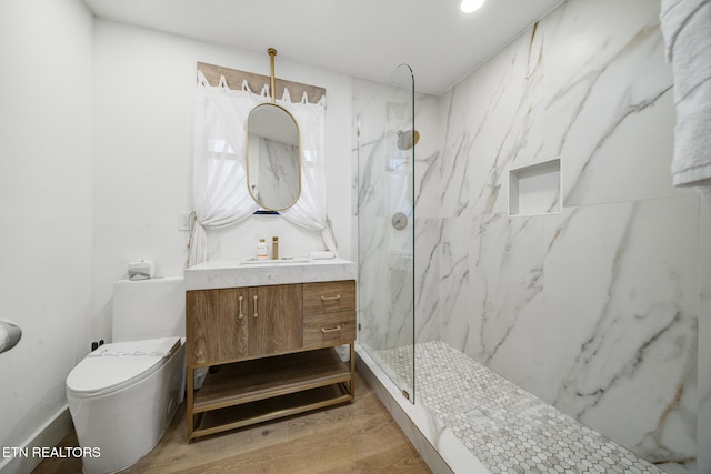 bathroom featuring a marble finish shower, toilet, vanity, and wood finished floors