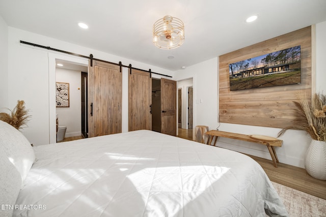 bedroom featuring a barn door, recessed lighting, and wood finished floors