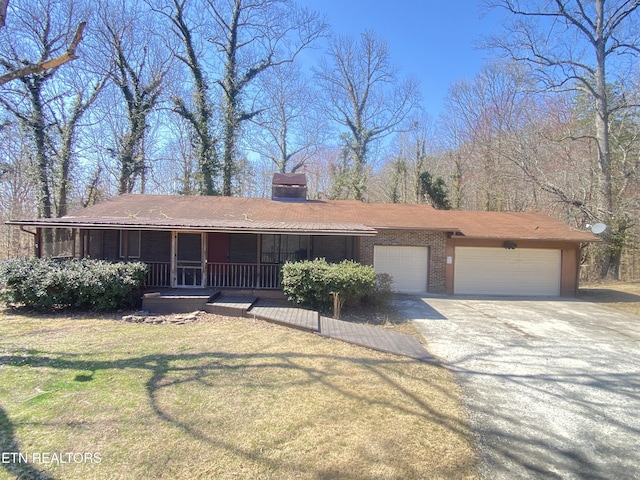 ranch-style home with a front yard, driveway, an attached garage, covered porch, and brick siding