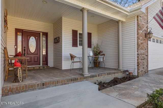 view of exterior entry featuring a porch, concrete driveway, and an attached garage