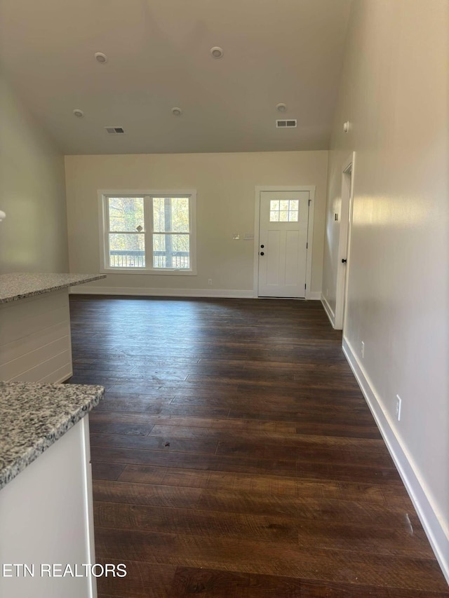 unfurnished living room featuring dark wood finished floors, baseboards, and visible vents