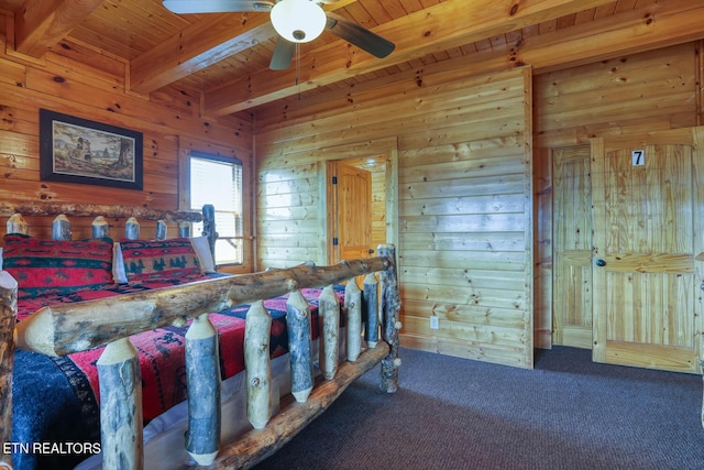 carpeted bedroom with beam ceiling, wood ceiling, wood walls, and a ceiling fan