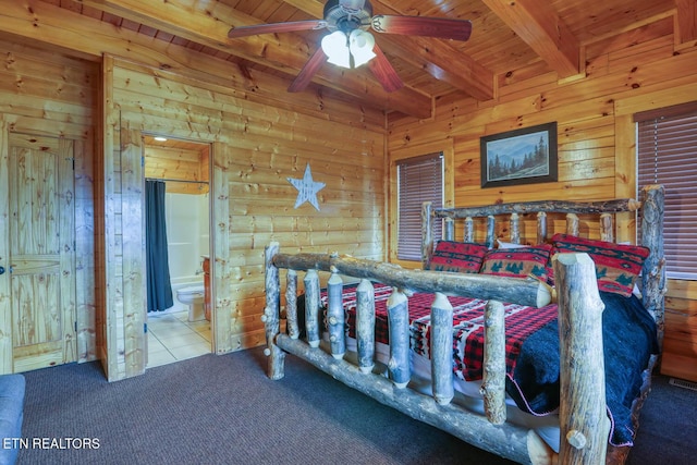 bedroom with beam ceiling, ensuite bath, carpet floors, wooden walls, and wooden ceiling