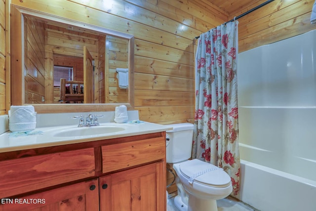 bathroom with vanity, wooden walls, toilet, and shower / tub combo