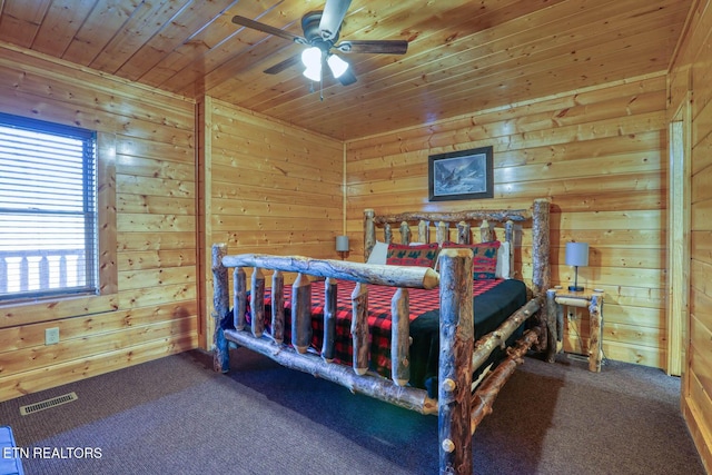 bedroom featuring visible vents, wood walls, wooden ceiling, and carpet