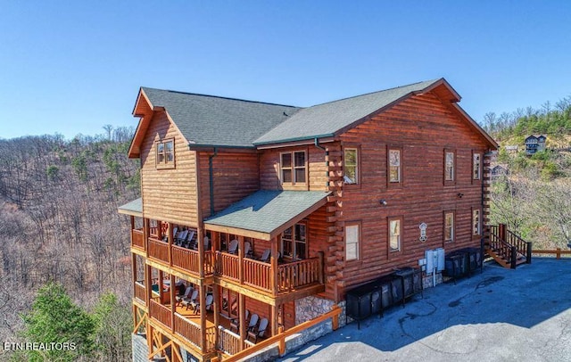 exterior space featuring log siding and roof with shingles