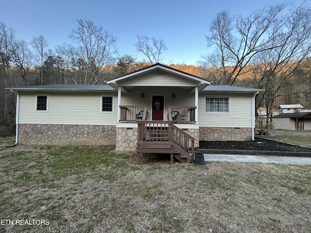 view of front facade with a front yard, covered porch, and crawl space