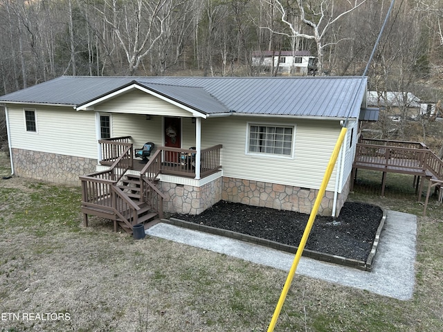 view of front facade featuring a deck, crawl space, stairs, and metal roof