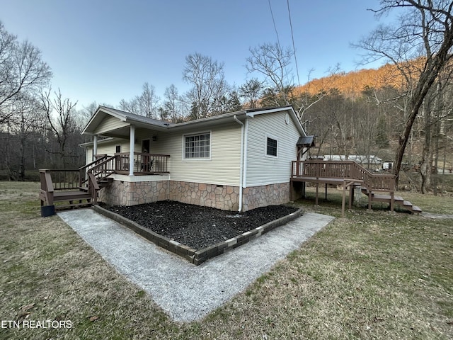 view of property exterior featuring stairway, a lawn, and a wooden deck