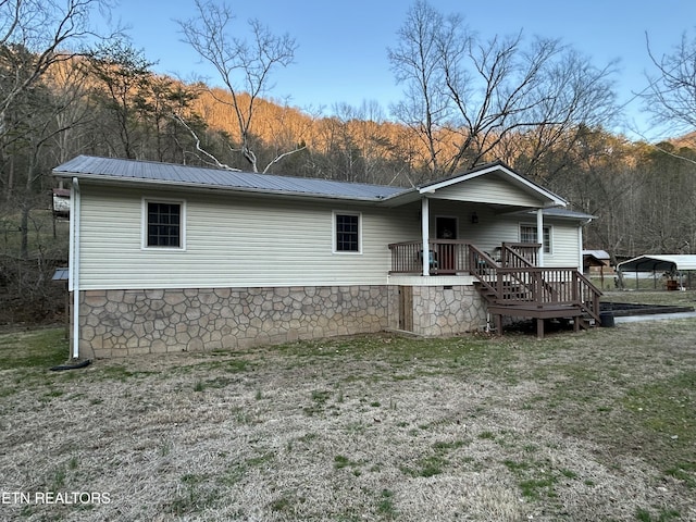 rear view of property with metal roof, a view of trees, and a yard