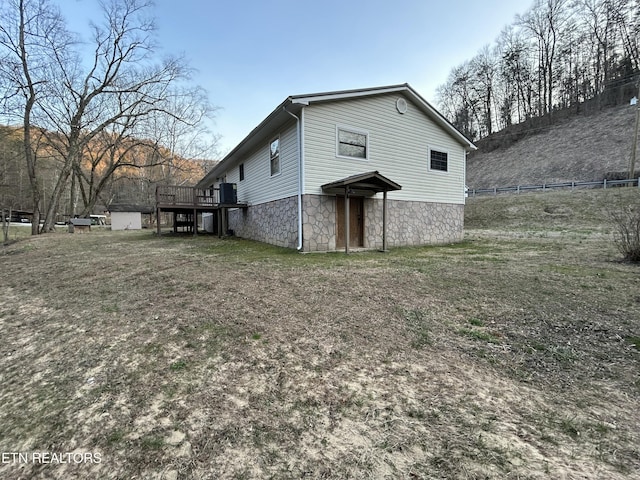 rear view of property with stone siding, a deck, and stairs