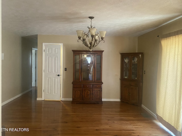 interior space with baseboards, a notable chandelier, wood finished floors, and a textured ceiling