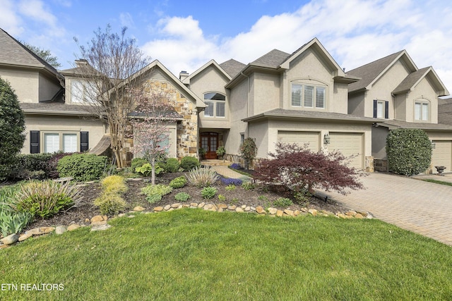 view of front of home with a front yard, stone siding, a garage, stucco siding, and decorative driveway