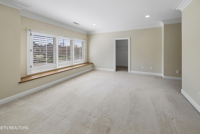 spare room featuring carpet, visible vents, baseboards, and crown molding