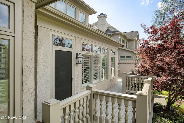 entrance to property featuring stucco siding and a wooden deck