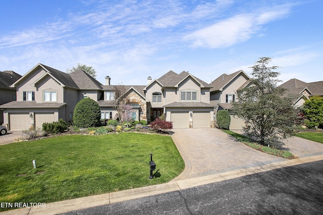 view of front of property with a garage, a residential view, a front lawn, and decorative driveway
