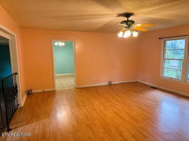 empty room featuring light wood finished floors, visible vents, a textured ceiling, and baseboards